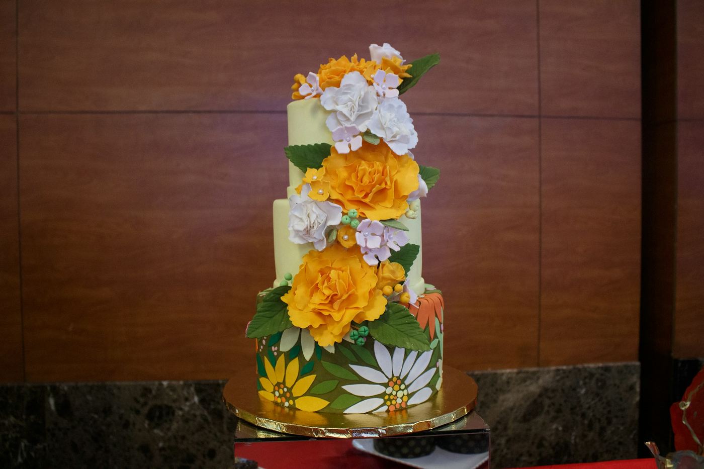 A three-tier cake decorated with yellow and white flowers